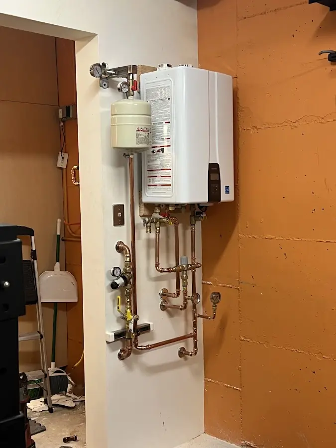 Plumbing technician inspecting water heater connections in Colchester